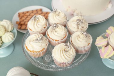 Turkuaz masadaki doğum günü partisi için lezzetli beyaz kekler ve diğer şekerlerle tatlı standı, yakın plan.