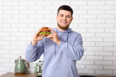 Mutfakta lezzetli burgeri olan genç bir adam.