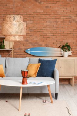 Sörf tahtası, rahat bir kanepe ve şık bir oturma odasında kahve masası.