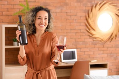 Evinde şişe ve bir bardak kırmızı şarapla orta yaşlı güzel bir kadın.