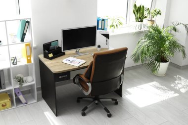 Çalışma yeri, koltuk, modern bilgisayar ve raf ünitesi olan ofis içi