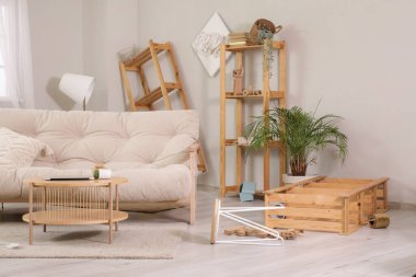 İçinde kanepe, masa ve raf üniteleri olan dağınık bir oturma odası.