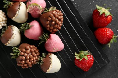 Siyah arka planda çikolata kaplı çilekler, yakın plan.