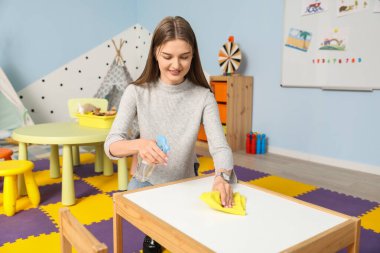 Anaokulunda kadın kreş öğretmeninin dezenfekte masası
