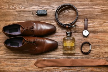 Parfüm şişeli erkek ayakkabıları ve ahşap arka planda aksesuarlar.