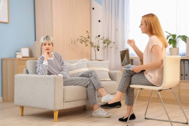 Üzgün genç kız psikologun ofisinde kanepede oturuyor.