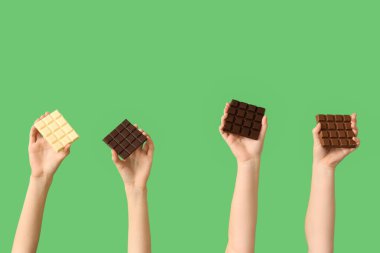Yeşil arka planda farklı çikolata çubukları olan kadın elleri.