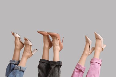 Gri arka planda farklı topuklu kadın bacakları.