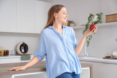 Mutfakta kırmızı elmalı genç bir kadın.