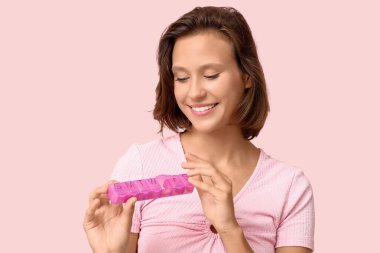 Pembe arka planda hap organizatörü olan güzel bir genç kadın.