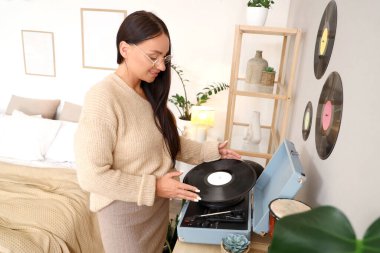 Yatak odasındaki tuvalette pikap kullanan genç bir kadın.