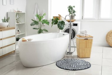 Yuvarlak paspası, çamaşır sepeti ve çamaşır makinesi olan banyonun içi.