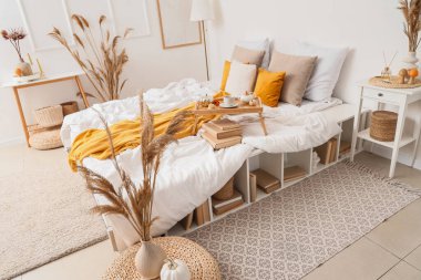 Yatak odası, raf ünitesi ve vazo dolusu otla kaplı.