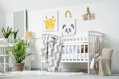 Ekoseli şık beyaz bir beşik ve çocuk odasının iç tarafındaki duvarda resimler.