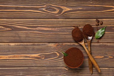 Tahta arka planda kahve tozu olan kâseler ve kaşıklar.