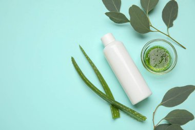 Turkuaz arka planda doğal kozmetik ürün, okaliptüs ve aloe vera yapraklarıyla kompozisyon