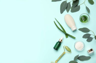 Farklı doğal kozmetik ürünlere sahip kompozisyon, yüz masajı silindiri, okaliptüs ve turkuaz arka planda aloe vera yaprakları