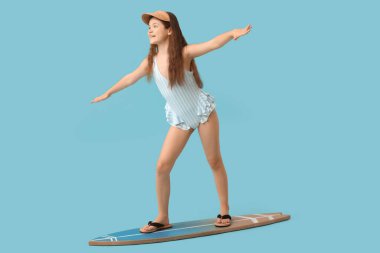 Mavi arka planda sörf tahtasında mayo giymiş tatlı bir kız.