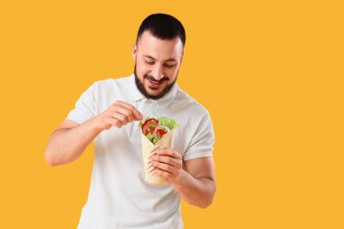 Sarı arka planda lezzetli sandviçli genç adam.