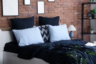 Modern yatak odasında siyah beyaz çarşaflı rahat bir yatak.