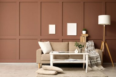 Oturma odasının içinde kanepe, cam masa ve boş çerçeveler var.