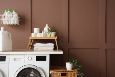 Çamaşır deterjanı, çamaşır makinesi ve havluların yanında dur.