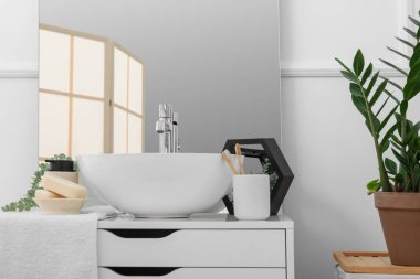 Lavabo, ayna ve banyo aksesuarları banyodaki çekmecelerin üzerinde.