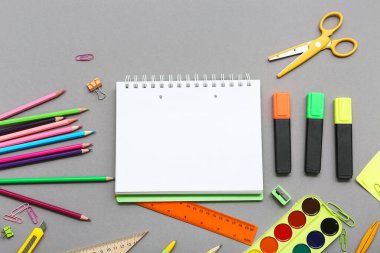 Gri arka planda kalem ve makaslı defter. Üst görünüm