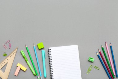 Not defteri, cetvel ve gri arka planda kalemler. Üst görünüm