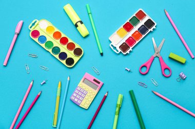 Suluboya boya, hesap makinesi ve makas mavi arka planda. Üst görünüm