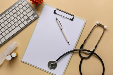 Bej arka planda modern bilgisayar klavyesi, kalem, pano ve steteskop