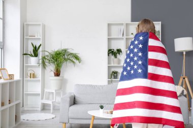 Oturma odasında Amerikan bayrağı olan bir kadın.