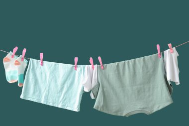 Temiz giysiler yeşil arka planda ipte asılı.