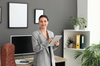 Şık bir ofiste koltuk ve işyeri yakınında tablet kullanan kadın ofis çalışanı