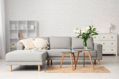 Gri kanepe ve sehpanın üzerinde nilüfer çiçekleri olan şık bir oturma odası.