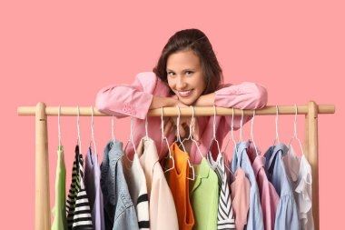 Pembe arka planda farklı giysileri olan güzel bir kadın.