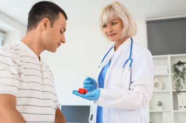 Tiroid bezi modelini klinikteki erkek hastaya gösteren kadın endokrinolog.