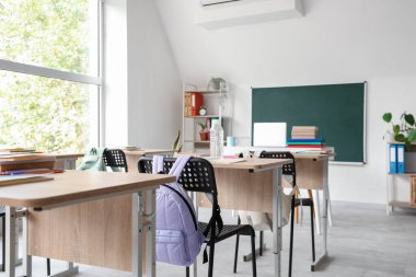 Masası ve tahtası olan aydınlık sınıfın içi