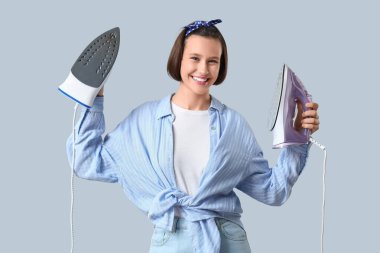 Gri arka planda ütüler ile genç kadın