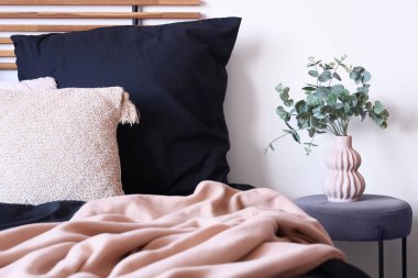 Rahat yataklı, siyah çarşaflı ve komodinli modern yatak odası.