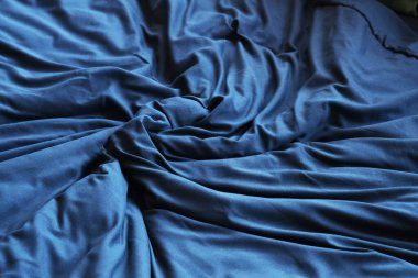 Buruşuk battaniyeli ve siyah çarşaflı rahat yatak, yakın plan.