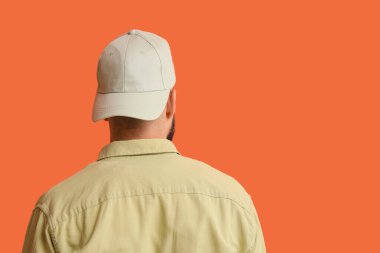 Turuncu arka planda şık şapkalı yakışıklı bir genç.