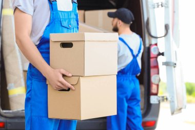 Dışarıdaki arabadan kutular taşıyan bir erkek taşıyıcı.