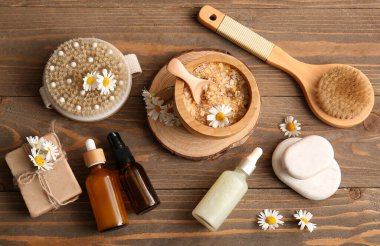 Papatya çiçekleri, masaj vücut fırçaları ve ahşap arka planda bulunan kozmetik ürünler, yakın plan.