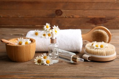 Papatya çiçekleri, masaj vücut fırçaları ve ahşap arka planda bulunan kozmetik ürünler, yakın plan.