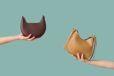 Turkuaz arka planda el çantalı kadın eller.