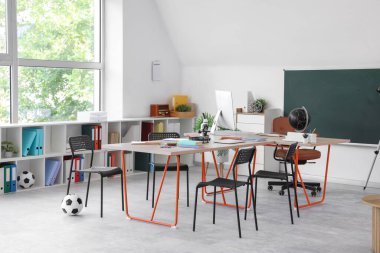 Masaları ve raf ünitesi olan öğretmenler odasının içinde.