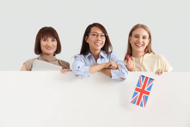 Açık arkaplanda boş posteri olan kadın öğretmenler