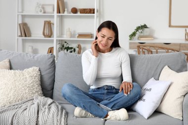 Evdeki kanepede kaşınan suçiçeği hastası genç bir kadın.