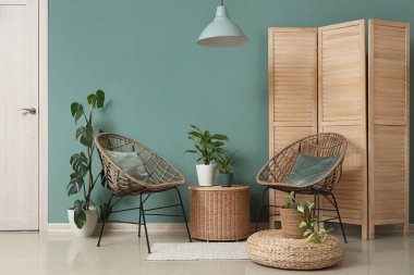 Sallanan lamba, koltuklar ve bitkilerle dolu bir oturma odası.